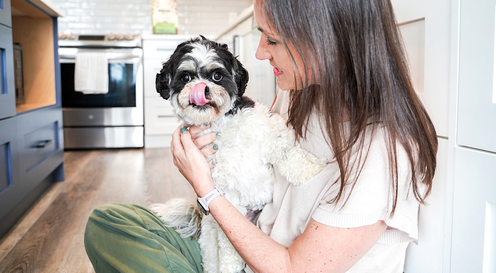 Dog licking its lips with owner in kitchen