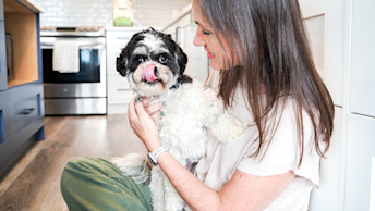 Dog licking its lips with owner in kitchen