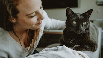 Woman with black cat on sofa