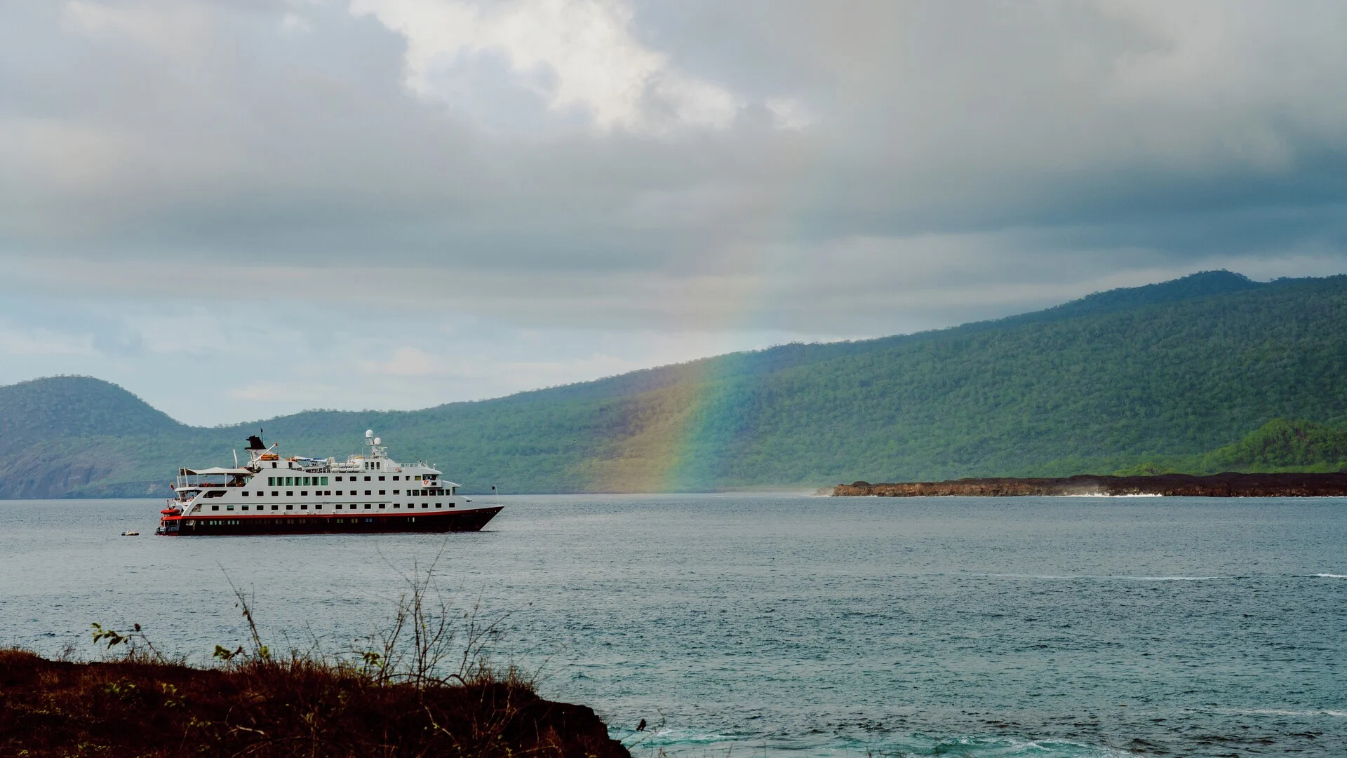 MS Santa Cruz II and a beautiful rainbow at the coast of Santiago island, Galápagos. Credit: Andres Mesias.