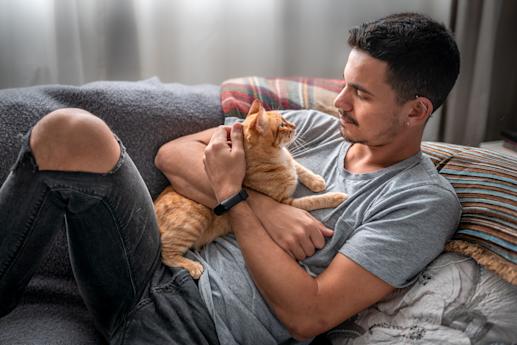 man sitting on couch with cat
