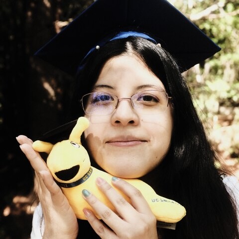 Headshot of a young woman in a mortarboard holding a yellow stuffed animal.}}
