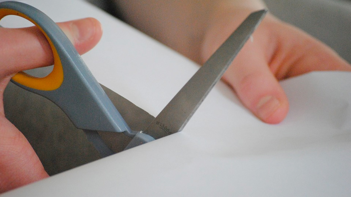 Hands cutting white paper with scissors