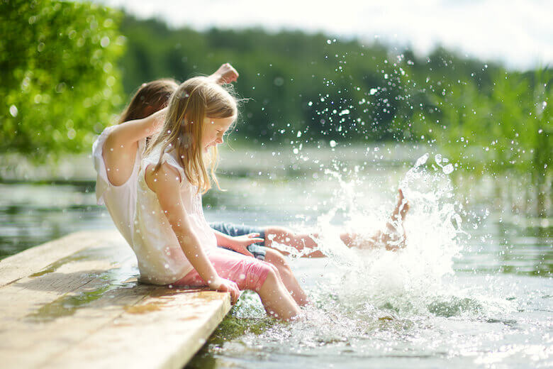 Campsite for children: sisters splash around together in a lake.