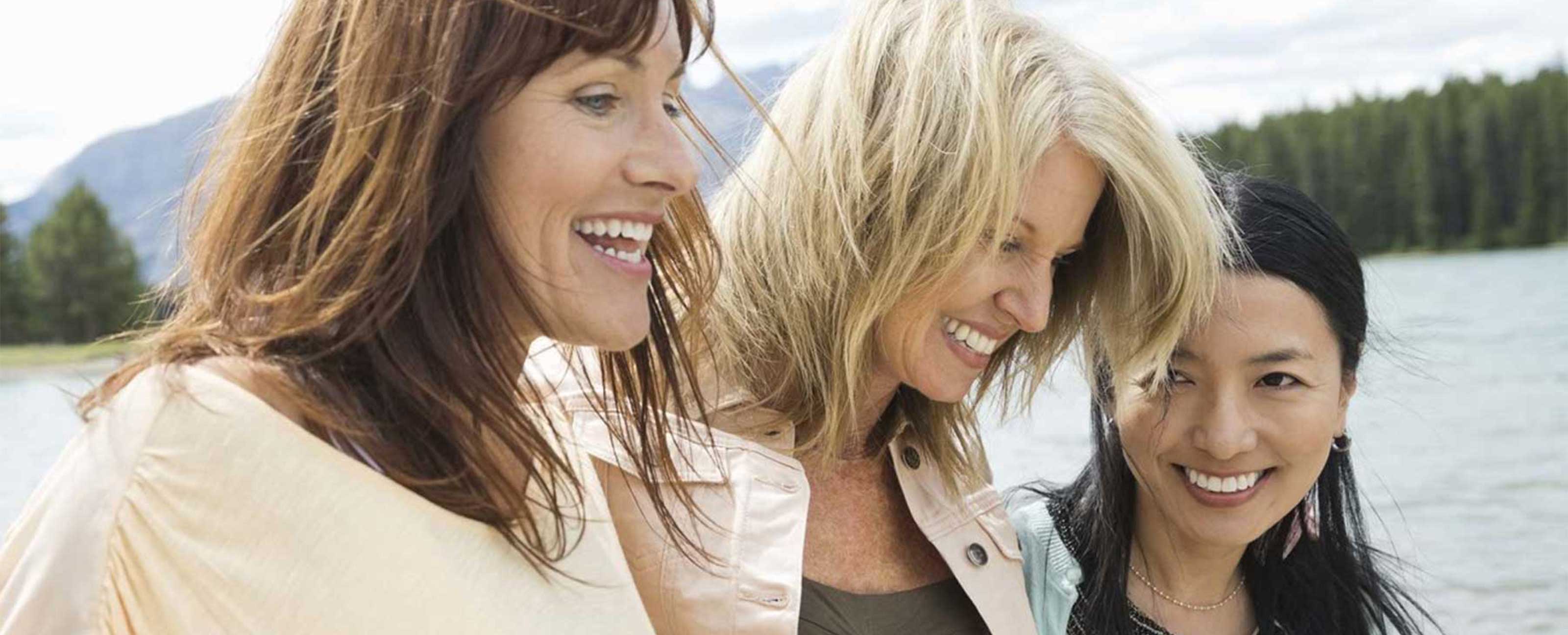 three women laughing by lake legacy image