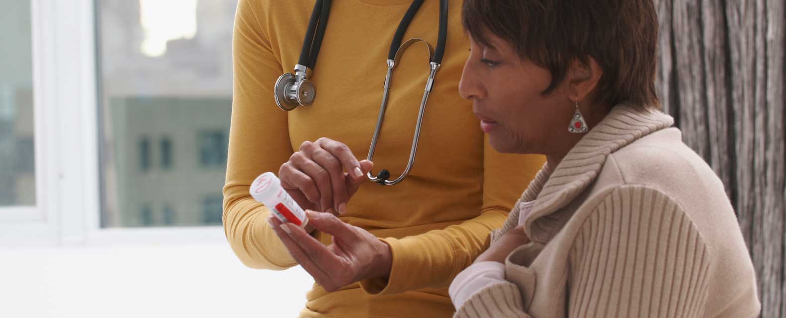 patient looking at medicine bottle being shown to her by doctor