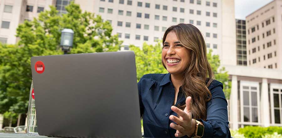 在莉莉公司中心外微笑的女人在笔记本电脑上工作