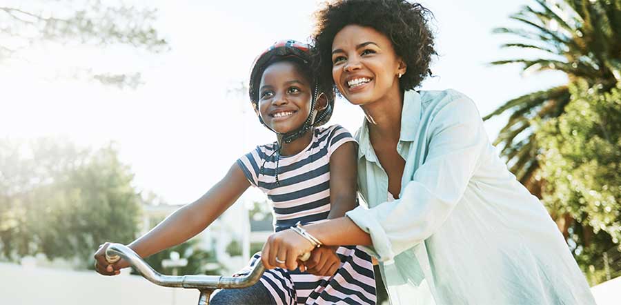 woman teaching a girl to ride a bike
