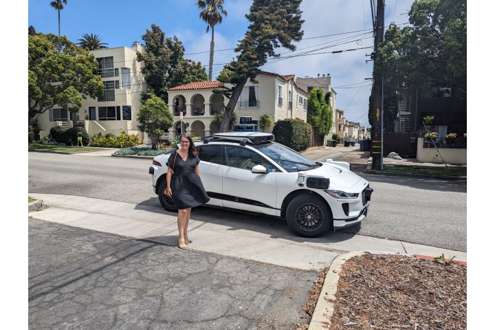 Sarah Wilson, executive director of Harvest Home, standing outside in Santa Monica next to a parked Waymo One vehicle