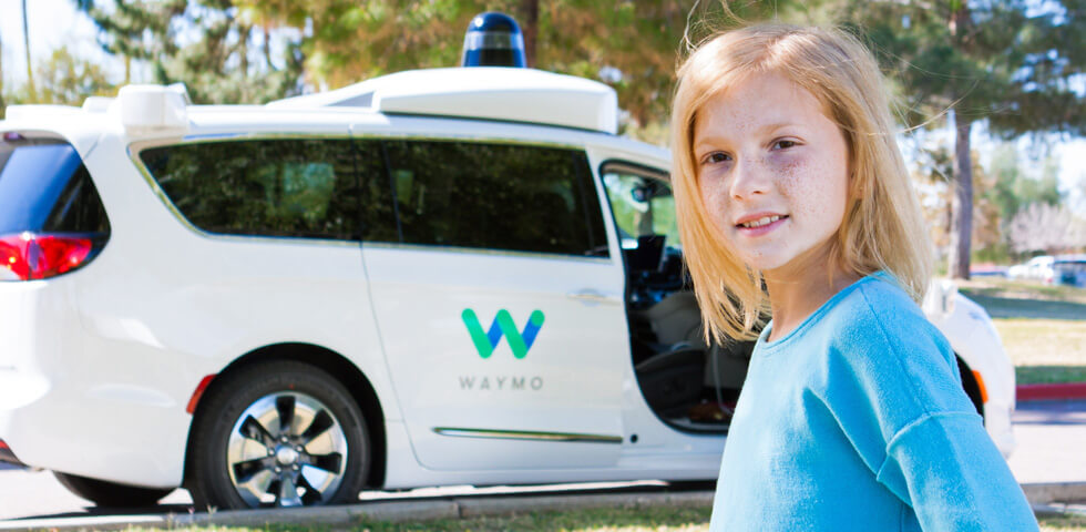 Girl in blue shirt in front of Waymo autonomous vehicle 