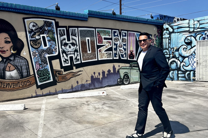 Oscar de la Salas walking in front of a "Phoenix" mural