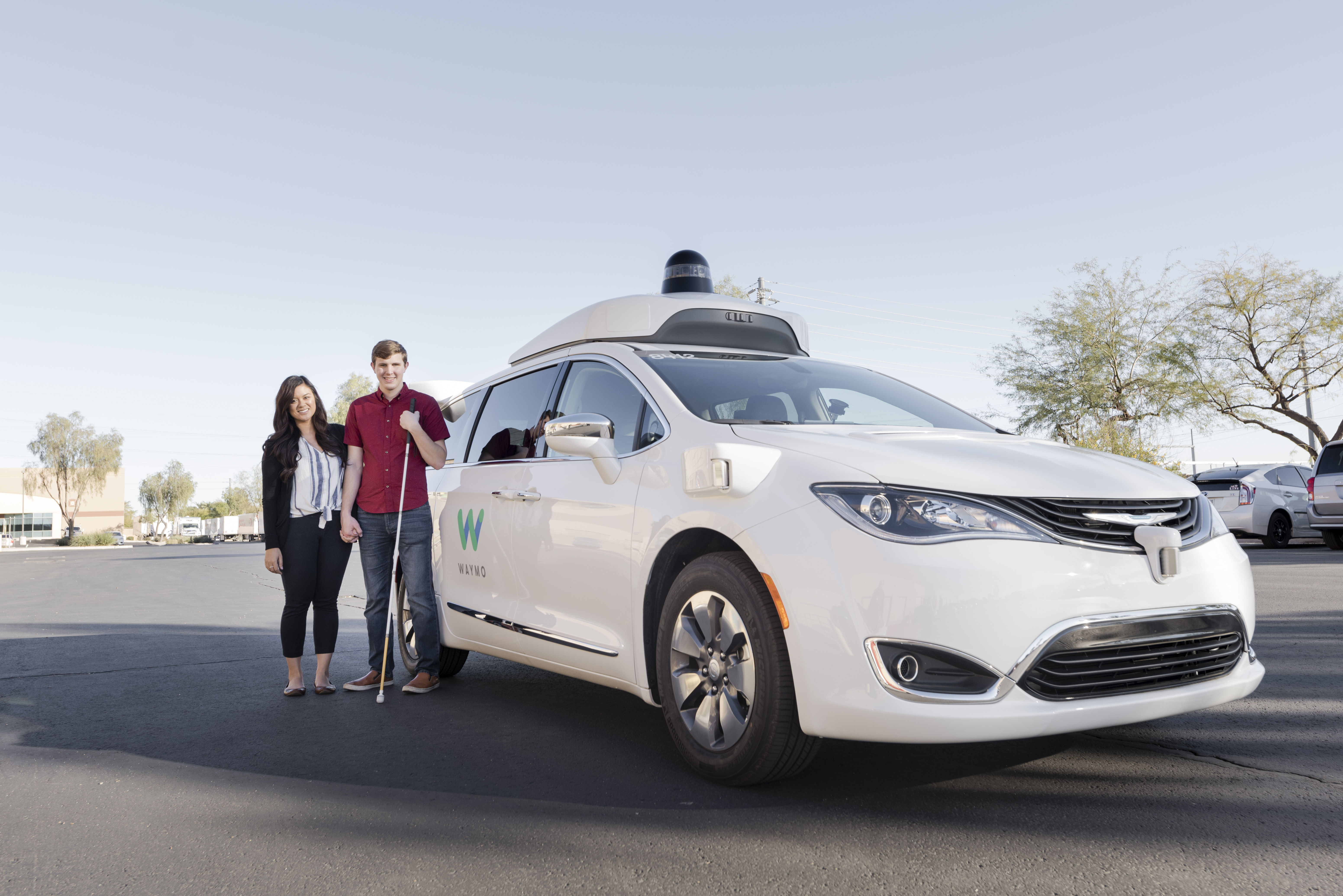 Max and Lillian outside next to a Waymo vehicle