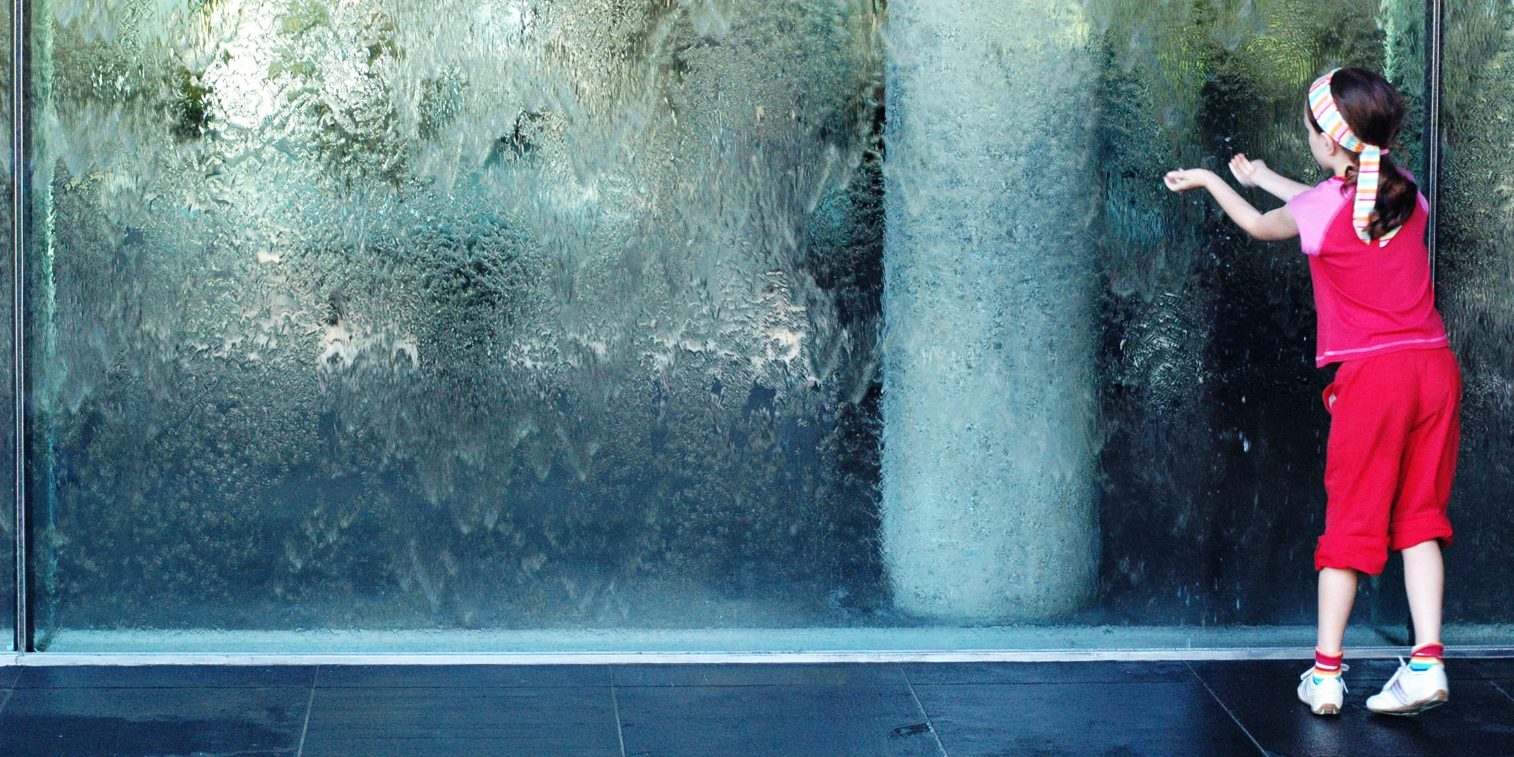 Kid at the waterfall glass at the entrance to the National Gallery of Victoria (NGV). 