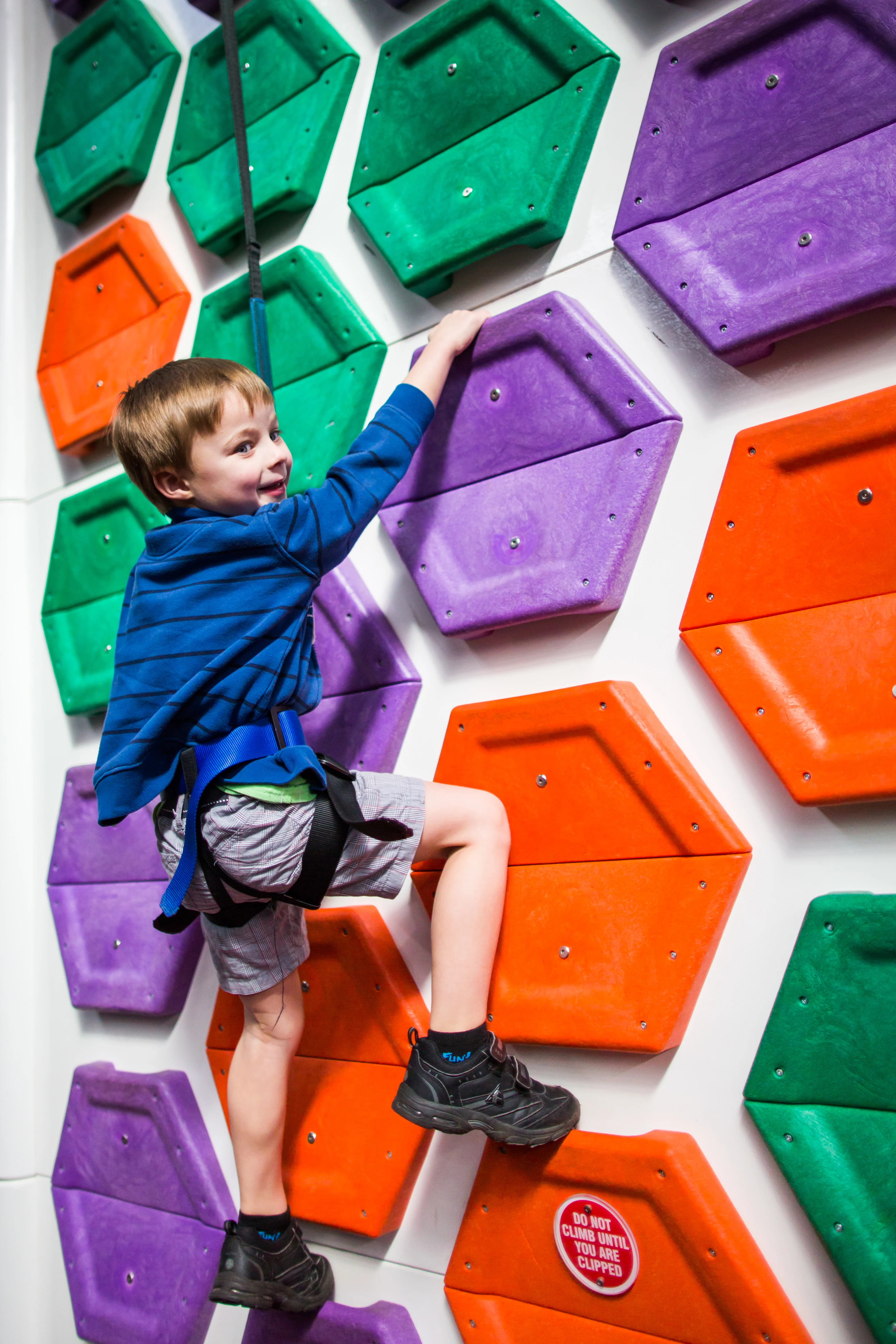 Kid climbing up a brightly coloured climbing wall at BOUNCEinc Geelong