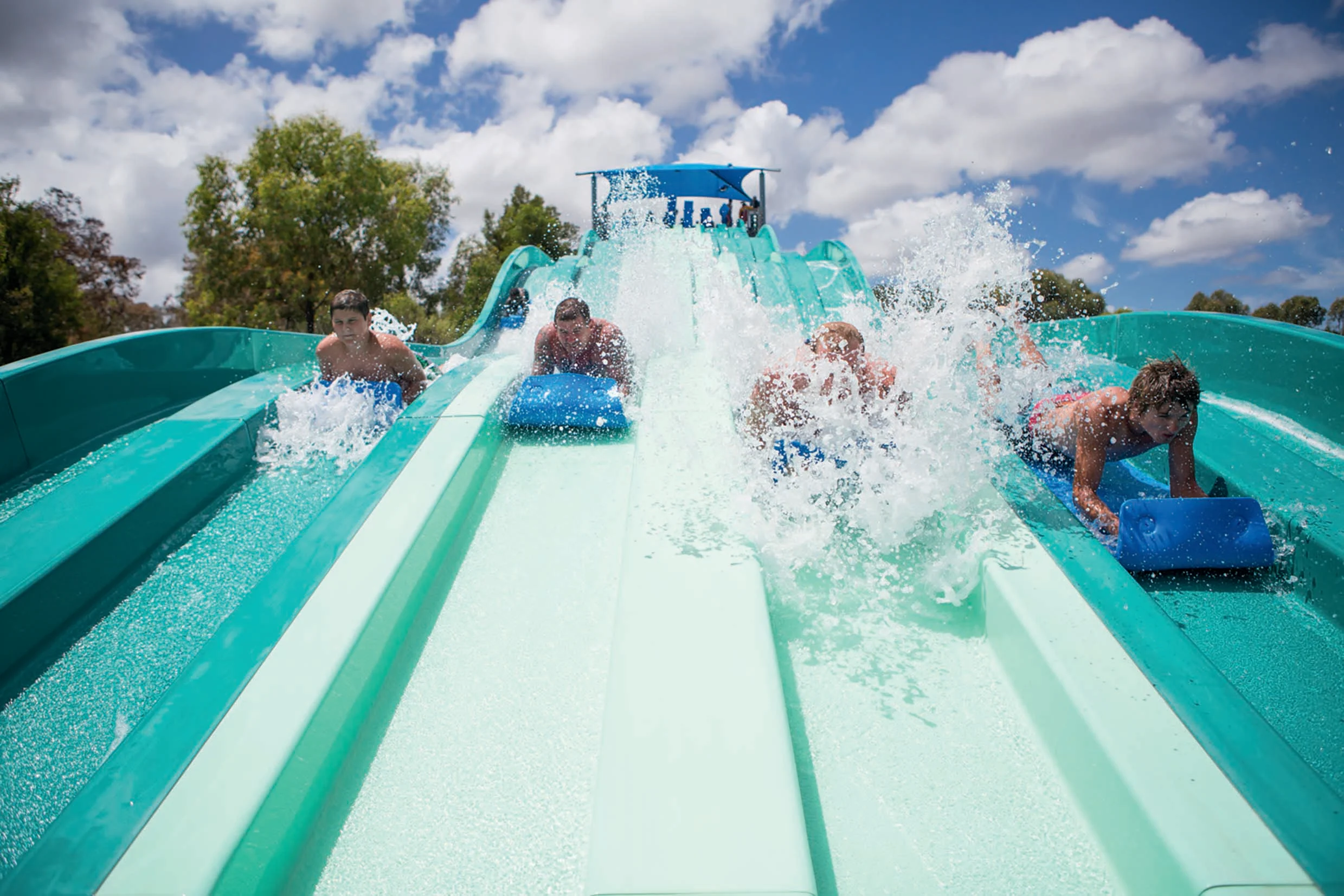 Adults and kids sliding down waterslides at Geelong Adventure Park, Victoria