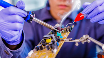 Engineer repairing electronic circuit board with soldering iron