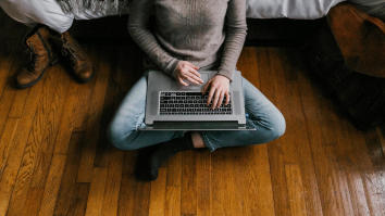Student sitting on floor typing on laptop