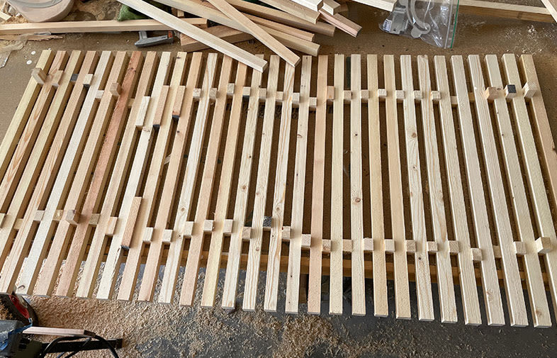 Rå träpanel med ljusa ribbor på verkstadsgolv med sågspån och träspill