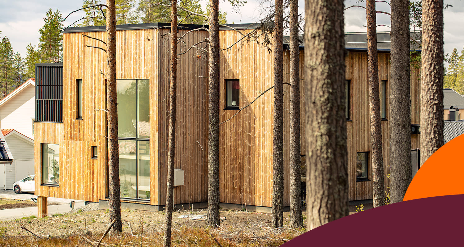 Ljust tvåvåningshus i träpanel med stora fönster bland tallar i förort