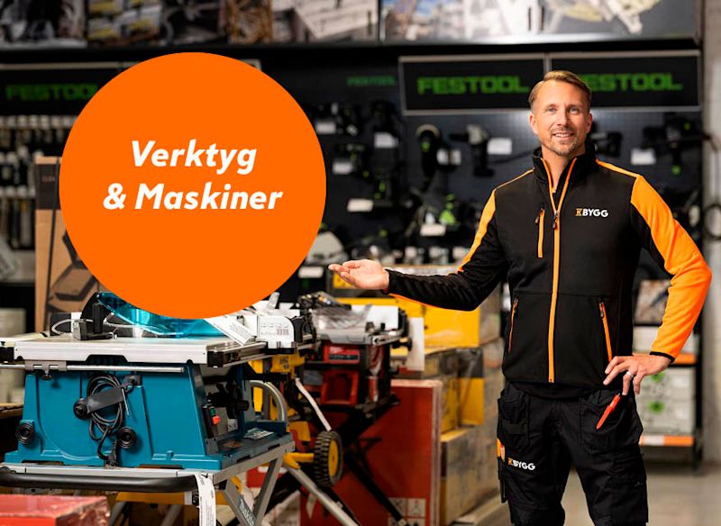 Medarbetare i svart/orange uniform pekar mot blått bordsåg under orange skylt “Verktyg & Maskiner”