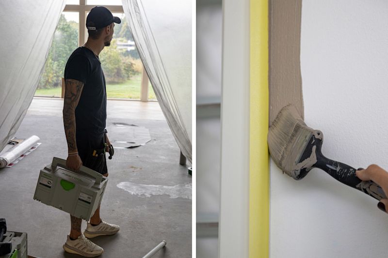 Hantverkare i tomt rum med verktygslåda. Pensel målar vit karm med beige färg och gult tejp.