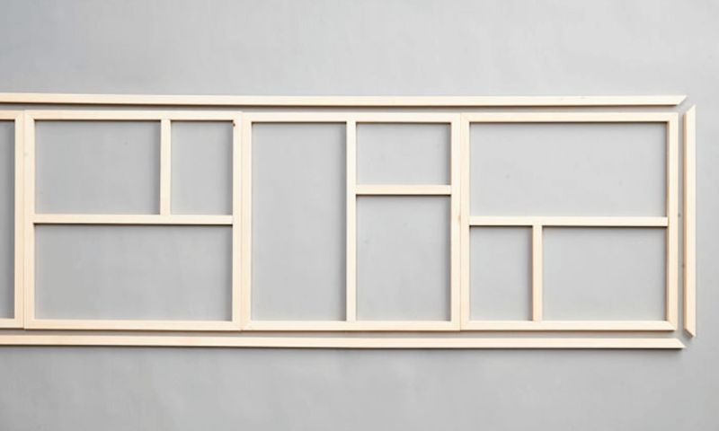 Liggande ljust träram med flera rektangulära fack mot grå bakgrund.