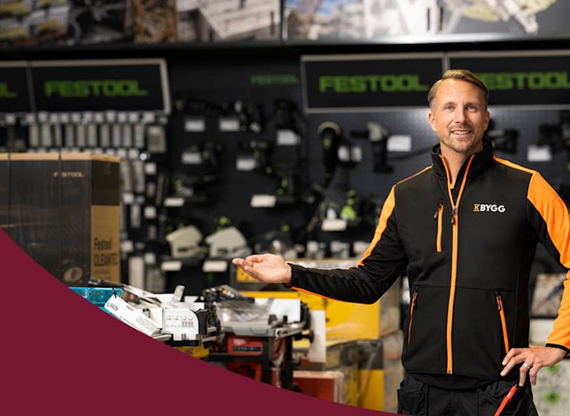 Bilden visar en personer som står i en verkstads- eller butiksmiljö med verktyg i bakgrunden. Den vänstra sidan har en vinröd färgöverlägg.