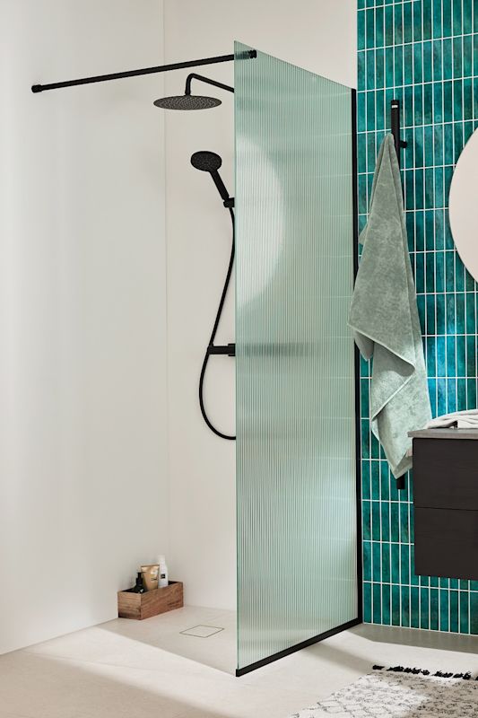 Modern duschhörna med svart regndusch, strukturglas, turkosa kakelväggar och grönt badlakan.