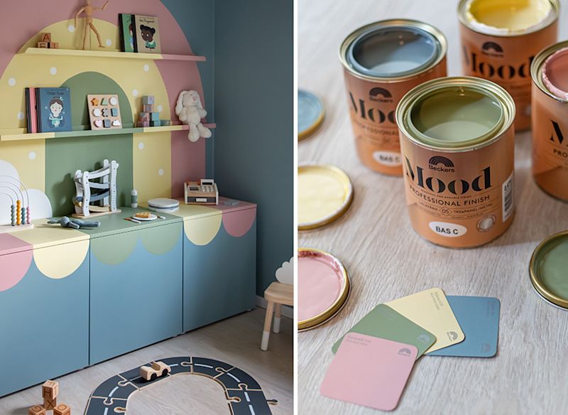 Pastellfärgat barnrum med blå skåp och rosa-gula mönster bredvid öppna målarburkar.