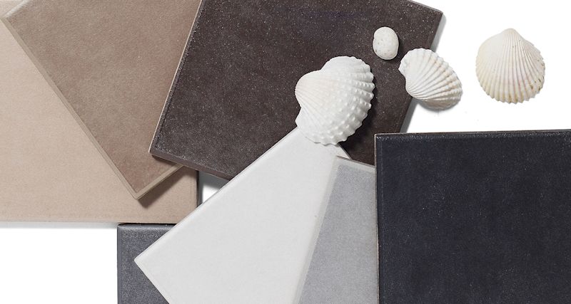 Överlappande kakelplattor i beige, brun, grå och svart med vita snäckskal på vit bakgrund.