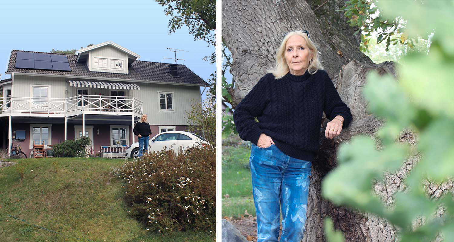 Grå villa med solpaneler och vit balkong, person i svart tröja och blå jeans lutad mot en ek.