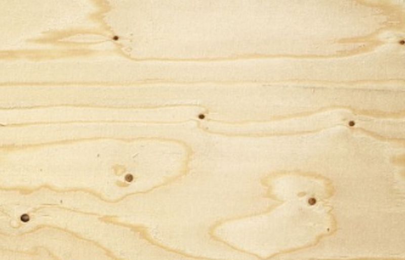 Ljust beige plywoodskiva med tydlig ådring och mörka knutar.