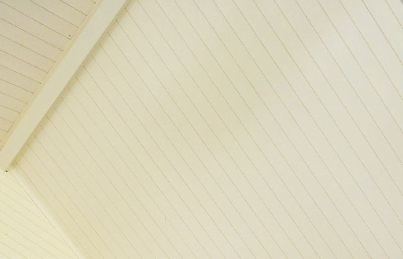 Inomhus snedtak i krämfärgade träpaneler med synlig bärande balk