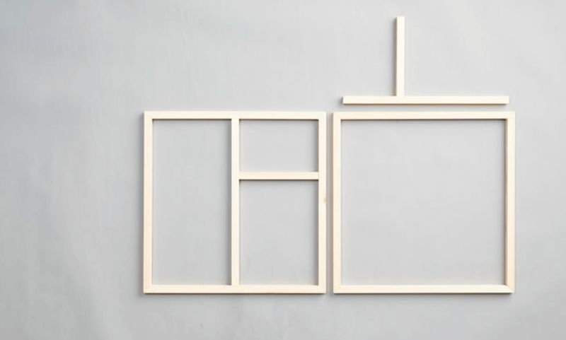 Två ljusa träramar med geometriska fack mot grå bakgrund