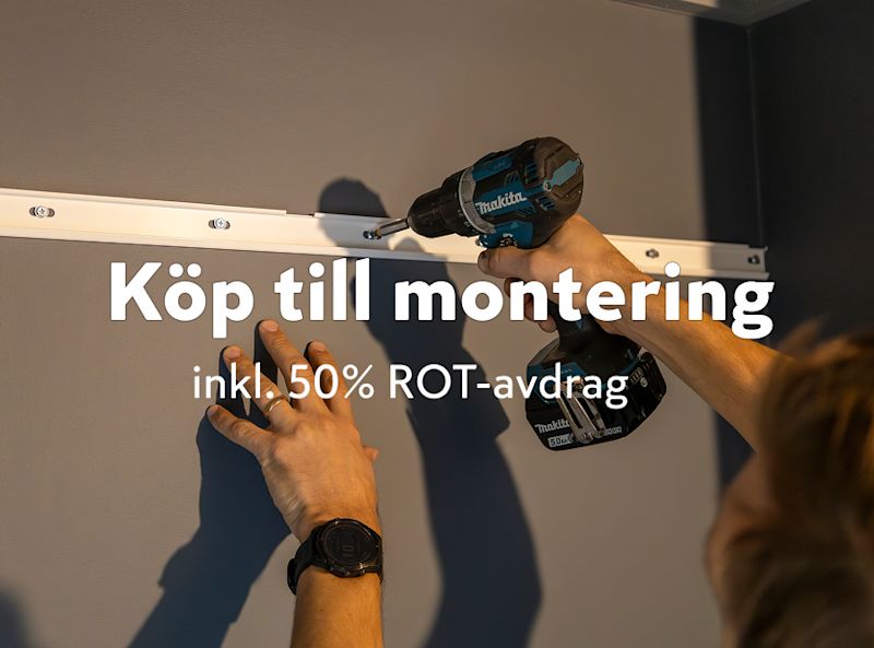 en person som använder en Makita borrmaskin för att montera ett vitt fäste på en grå vägg. Texten i bilden lyder: "Köp till montering inkl. 50% ROT-avdrag".