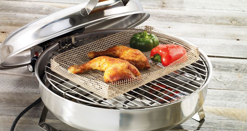 Öppen rostfri elgrill med två gyllene kycklingklubbor och grön samt röd paprika i grillkorg