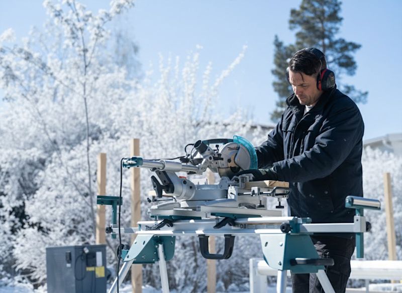 Man i grå t-shirt borrar trallbräda med batteridriven skruvdragare på solig uteplats.