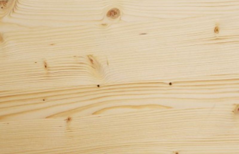 Närbild av obehandlad ljus träplanka med synliga ådror och kvistar.
