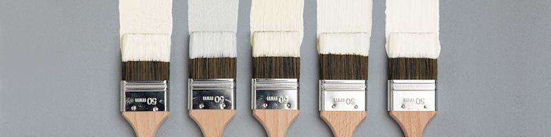 Fem träpenslar med 50 mm metallfäste doppade i vit färg på ljusgrå bakgrund.