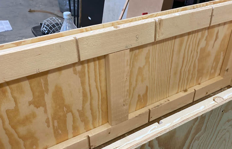 Råa ljusa plywoodskivor med vertikala reglar i verkstadsmiljö