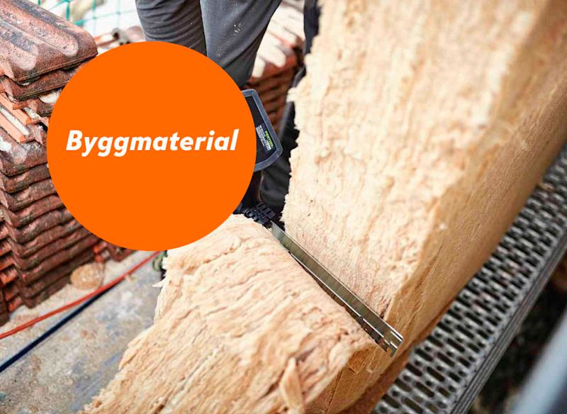 Arbetare sågar tjock mineralullsskiva med sticksåg, tegelröda takpannor i bakgrunden.