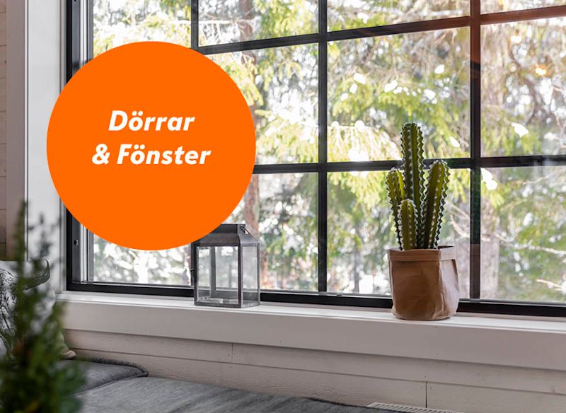 Svartgrindat fönster, orange cirkel ’Dörrar & Fönster’, kaktus och lykta på vit fönsterbräda