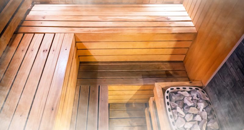 ett basturum med ånga, ljus träpanel och aggregat med varma stenar