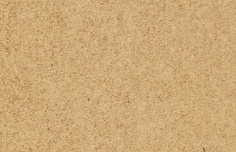 Närbild av kornig beige korkyta med små mörka fläckar.