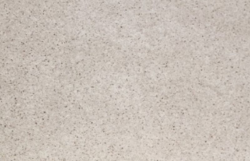 Närbild på en beige, kornig yta med små mörka prickar.