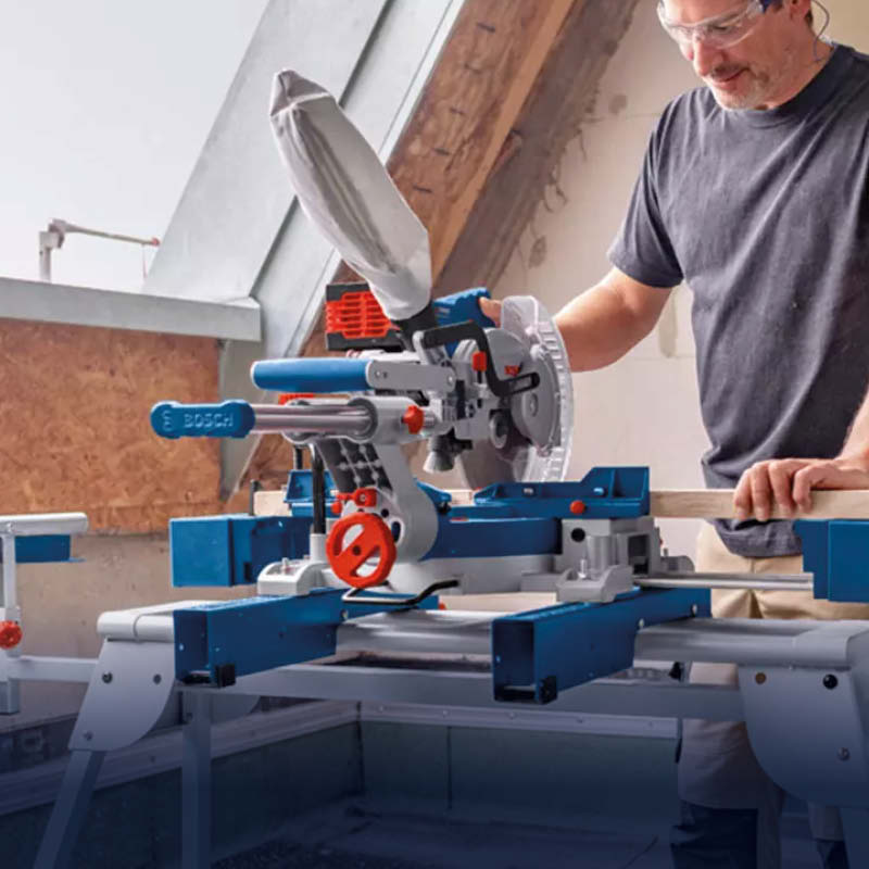 Arbetare manövrerar blå-grå Bosch geringssåg på stabil ställning under snedtak.