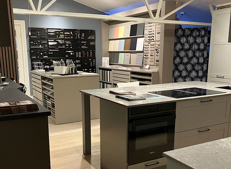 Interiör av köksshowroom med marmorbänk, induktionshäll, ugn, färg- och beslagprover