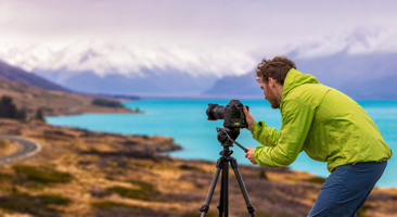 Image of photographer taking a picture overlooking the mountains and water