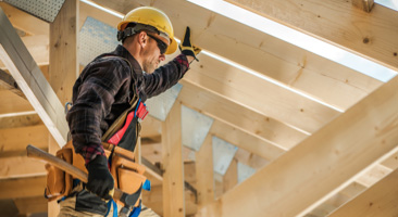 man holding up wooden beam at construction site