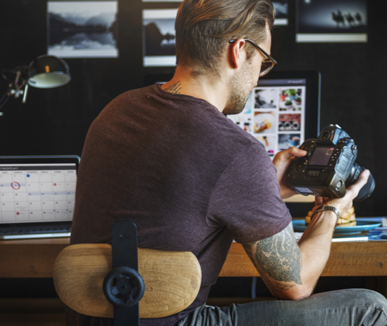 Photographer looking at his camera with his photography website in the background